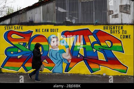 Derby, Derbyshire, Regno Unito. 28 aprile 2020. Una donna cammina oltre Covid-19 correlato Street art durante il blocco pandemico coronavirus. Credit Darren Staples/Alamy Live News. Foto Stock