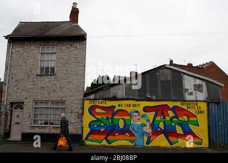 Derby, Derbyshire, Regno Unito. 28 aprile 2020. Un uomo cammina oltre Covid-19 correlato arte di strada durante il blocco pandemico coronavirus. Credit Darren Staples/Alamy Live News. Foto Stock