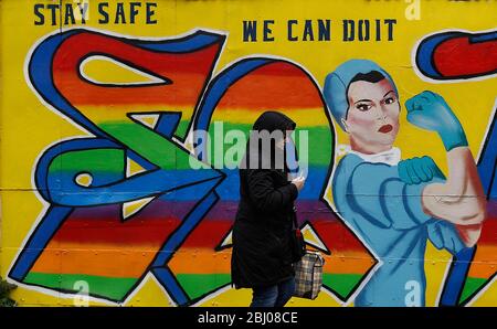 Derby, Derbyshire, Regno Unito. 28 aprile 2020. Una donna cammina oltre Covid-19 correlato Street art durante il blocco pandemico coronavirus. Credit Darren Staples/Alamy Live News. Foto Stock