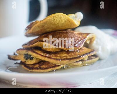 Pancake per la colazione preparati con una pastella di banana, due uova e 2 cucchiai di farina di grano saraceno, e un manfuil di mirtilli, cucinati in un po' di C Foto Stock