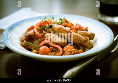 Piatto spagnolo di salsicce chorizo con peperoni rossi, pomodori, zucchine e salsa di vino rosso Foto Stock