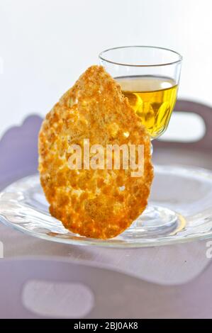 Biscotto tuile con un piccolo bicchiere di vino da dessert su un piatto di vetro - Foto Stock