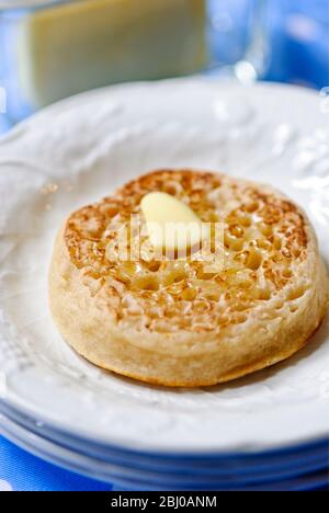 Tradizionale crumpet al burro caldo su piatto bianco - Foto Stock