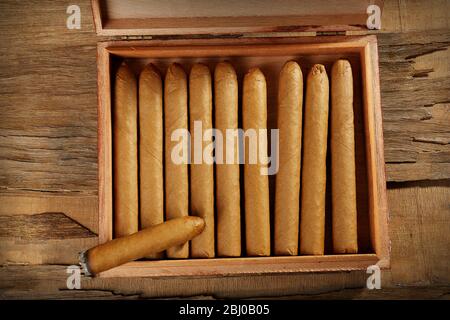 Sigari e bruciare uno nella scatola su tavolo di legno, vista dall'alto Foto Stock