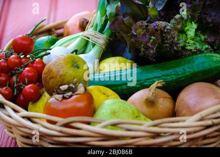 Cesto di frutta e verdura fresca su superficie rossa - Foto Stock