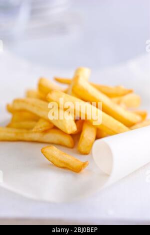 Pile di patatine fritte su carta verde - Foto Stock