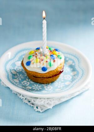 Muffin decorato come una prima torta di compleanno con icin gand candela singola bruciare - Foto Stock