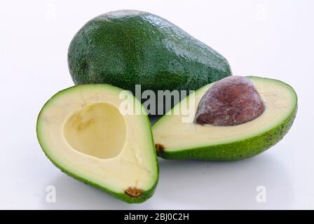 Pera di avocado fresca intera e tagliata su sfondo bianco - Foto Stock