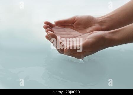 Le mani femminili sopra acqua chiara sfondo Foto Stock