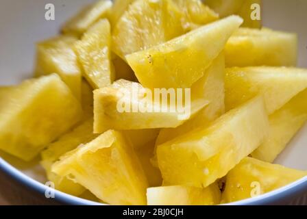 Pezzi di ananas interi appena tagliati in una ciotola bianca - Foto Stock