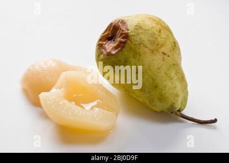 Confronto tra pera fresca cruda, che inizia a marcire con pere in scatola che mostrano il vantaggio della frutta in scatola. - Foto Stock