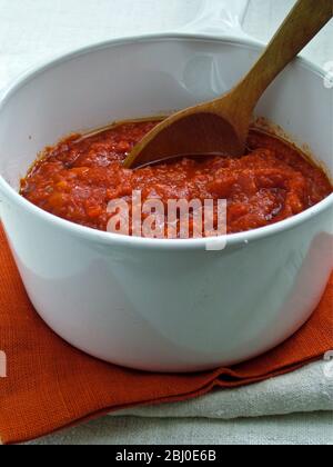 Preparare il salsa di tonato in una pentola bianca in ceramica, mescolando con un cucchiaio di legno - Foto Stock