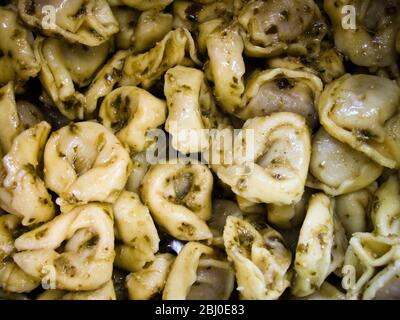 Primo piano di tortelloni cotti in salsa di pesto in padella - Foto Stock