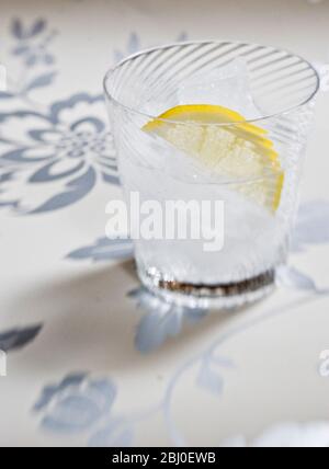 Vetro soffiato a spirale fine di spirito chiaro con soda o tonico, e fetta di limone su sfondo decorativo - Foto Stock
