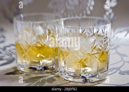 Scotch whisky su ghiaccio in vetro di cristallo di piombo tagliato su superficie decorativa argento - Foto Stock