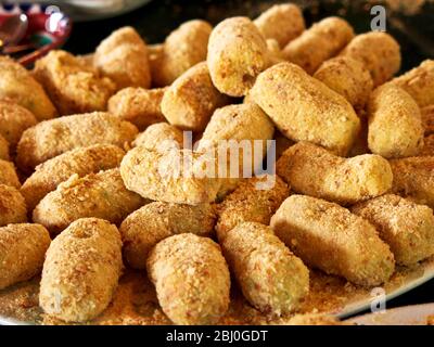 Piatto pieno di crocchette di patate appena fatte. Latte, condimento, cipolla tritata, tuorli d'uovo sbattuti e farina vengono aggiunti alle purè di patate. Sono bambini Foto Stock