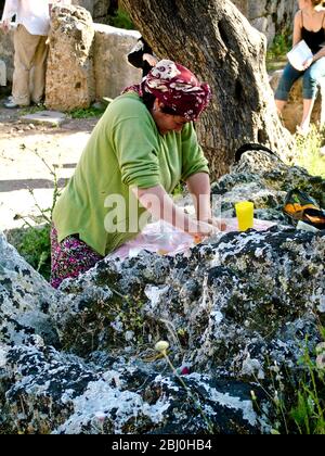 Donna che spreme arance per vendere bicchieri di succo fresco ai turisti in antico anfiteatro greco, Turchia meridionale - Foto Stock