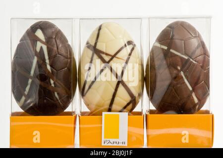 Tre uova di Pasqua simili al cioccolato - cioccolato al latte, alla lacca, in scatole di cellophane. - Foto Stock