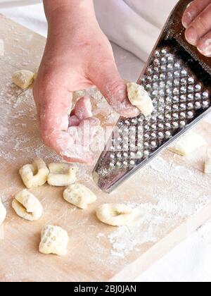 Pezzetti di pasta di gnocchi arrotolabili su una grattugia di scorza di limone, per modelli e dare loro consistenza. - Foto Stock