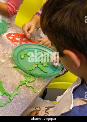 Bambini che tagliano fuori le forme decorative di Natale dalla glassa fondente colorata per decorare le torte - Foto Stock