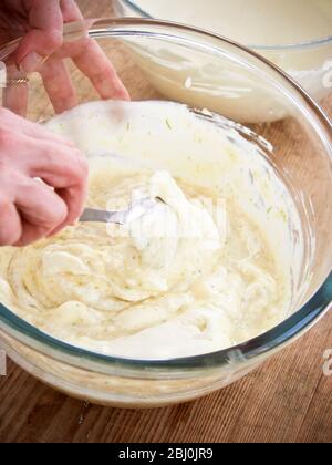 Mescolando la panna montata in crema di uova raffreddata e addensata con gelatina e scorza di lime per il dessert trifle. - Foto Stock