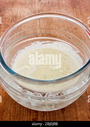Crema di crema addensata con gelatina e glime Zest raffreddando in una ciotola che riposa in una ciotola più grande di acqua ghiacciata - Foto Stock