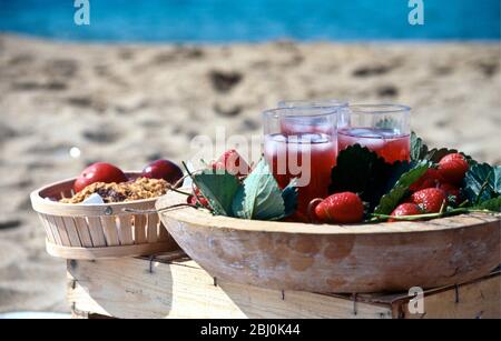 Succo di fragole in bicchieri alti con ghiaccio sul vassoio decorato con fragole e foglie di fragole - Foto Stock