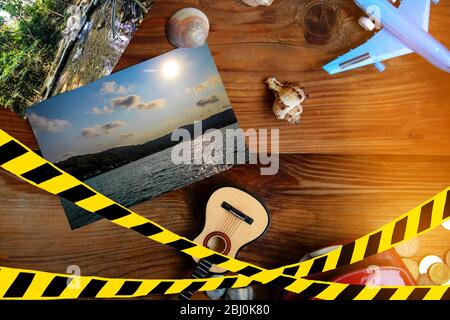 Composizione di viaggio su sfondo di legno. Nastro barriera - quarantena, isolamento, divieto di ingresso. Concetto di Covid-19. Foto Stock