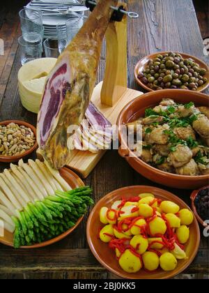 Tavolo a buffet di piatti spagnoli, incluso jamÑn iberico, su speciale stativo di intaglio - Foto Stock