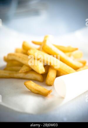 Pile di patatine fritte su carta verde - Foto Stock