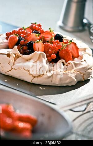 Pavlova con frutti di bosco freschi sul piano di lavoro della cucina - Foto Stock