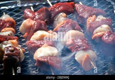 Grigliare il capesante e bistecche kebab su una griglia barbecue a carbone - Foto Stock