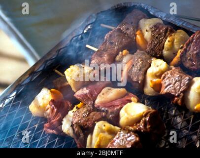 Grigliare il capesante e bistecche kebab su una griglia barbecue a carbone - Foto Stock