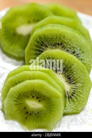 Fette di kiwi sbucciato su piatto bianco testurizzato - Foto Stock
