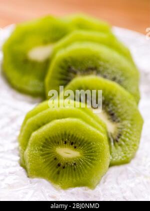 Fette di kiwi sbucciato su piatto bianco testurizzato - Foto Stock