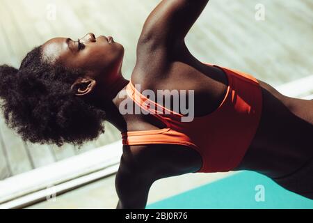 donna fitness che fa yoga stretches. Donna africana in abbigliamento sportivo che esercita yoga. Foto Stock