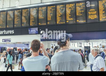 Londra/UK-1/8/19:giovani uomini in attesa del loro treno alla stazione di London Waterloo in un'ora di punta. Terminal del centro di Londra sulla rete ferroviaria nazionale Foto Stock