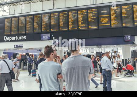 Londra/UK-1/8/19:giovani uomini in attesa del loro treno alla stazione di London Waterloo in un'ora di punta. Terminal del centro di Londra sulla rete ferroviaria nazionale Foto Stock