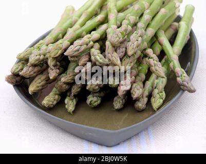 Mazzo di asparagi su piastra verde - Foto Stock