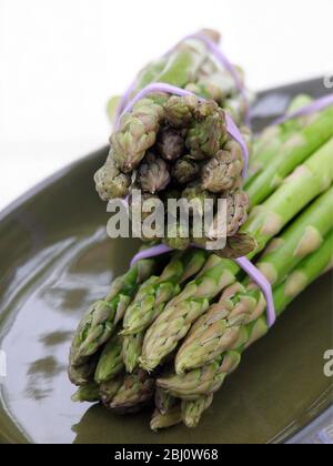 Due mazzi di asparagi su piastra verde - Foto Stock