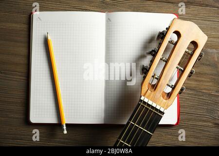 Scena di registrazione musicale con chitarra classica e notebook su tavolo di legno, primo piano Foto Stock