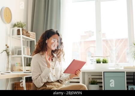 Giovane donna moderna che indossa elegante video conferenza con i suoi colleghi mentre si è a casa Foto Stock
