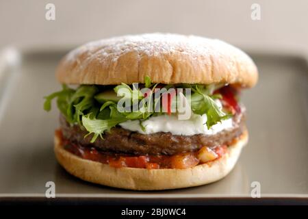Hamburger alla griglia in panino con insalata di frisee, cetrioli, strisce di pepe, panna acida e salsa di pomodoro - Foto Stock