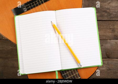 Scena di registrazione musicale con chitarra e memo pad su tavolo di legno, primo piano Foto Stock