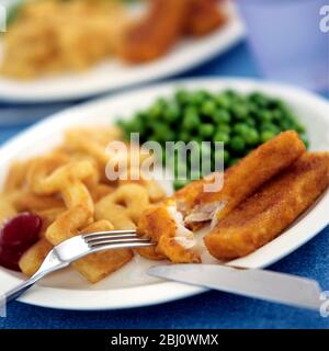 Cod dita di pesce sul piatto del bambino con scaglie di alfabeto e piselli verdi e ketchup di pomodoro - Foto Stock