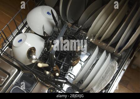 Lavate il contenuto della lavastoviglie caricata dopo il lavaggio in cucina moderna con pavimento in legno - Foto Stock