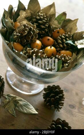 Decoro di Natale ciotola con foglie dorate, conetti di abete e kumquats stuoded con chiodi di garofano. - Foto Stock