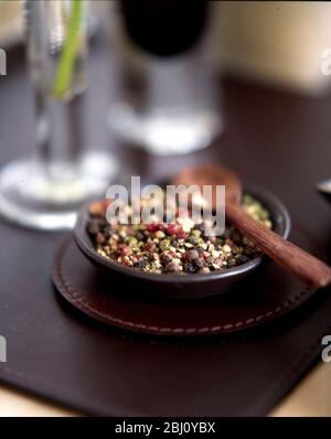 Piccolo piatto di pepe tritato misto con cucchiaio di legno - Foto Stock