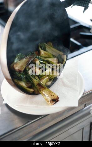 Cottura dei pakchoi in olio di sesamo caldo e cosparso di salsa di soia - Foto Stock
