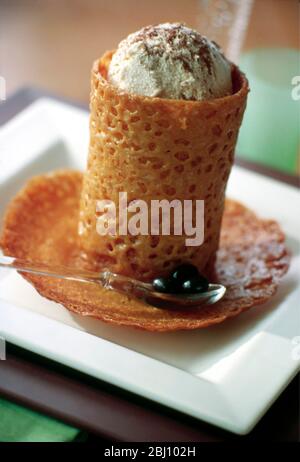 Tazza da caffè espresso con biscotti tipo brandy snap ripieni di gelato al caffè e ricoperti di polvere di cacao come dessert decorativo per d Foto Stock